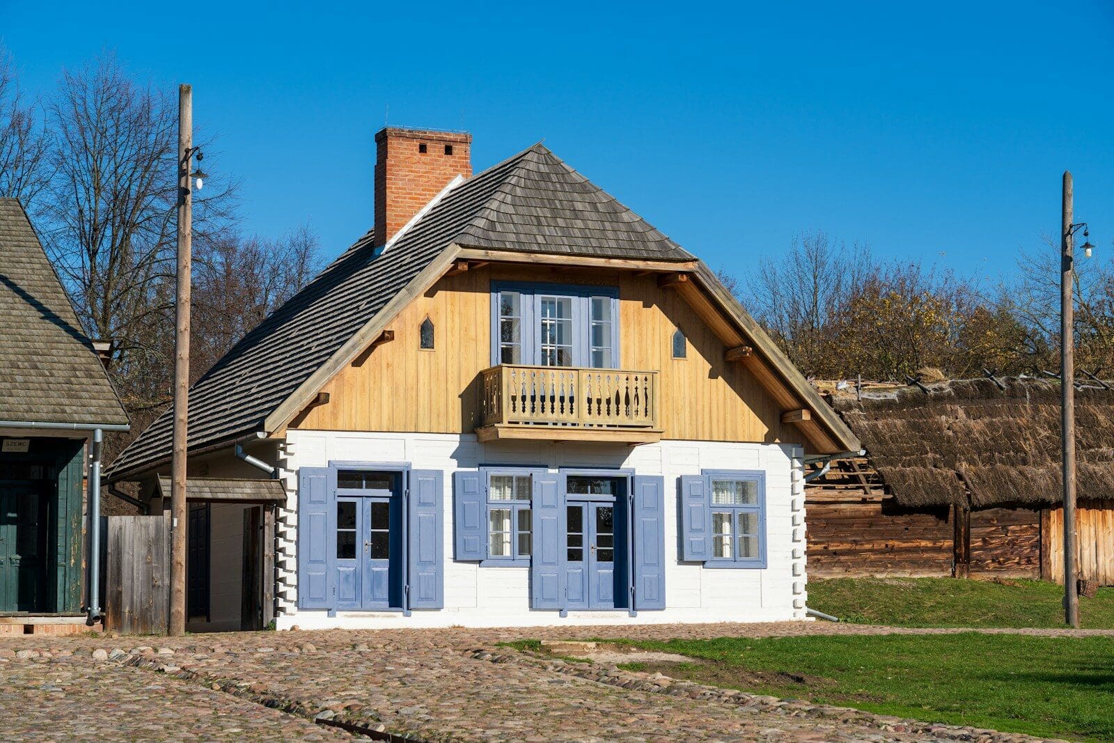 a small house with blue shutters and a balcony